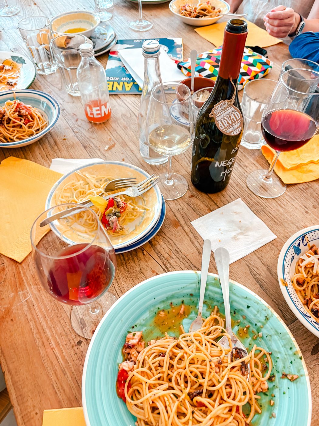 Mesa do Tide & Tannin com esparguete, copos de vinho e uma garrafa algarvia
